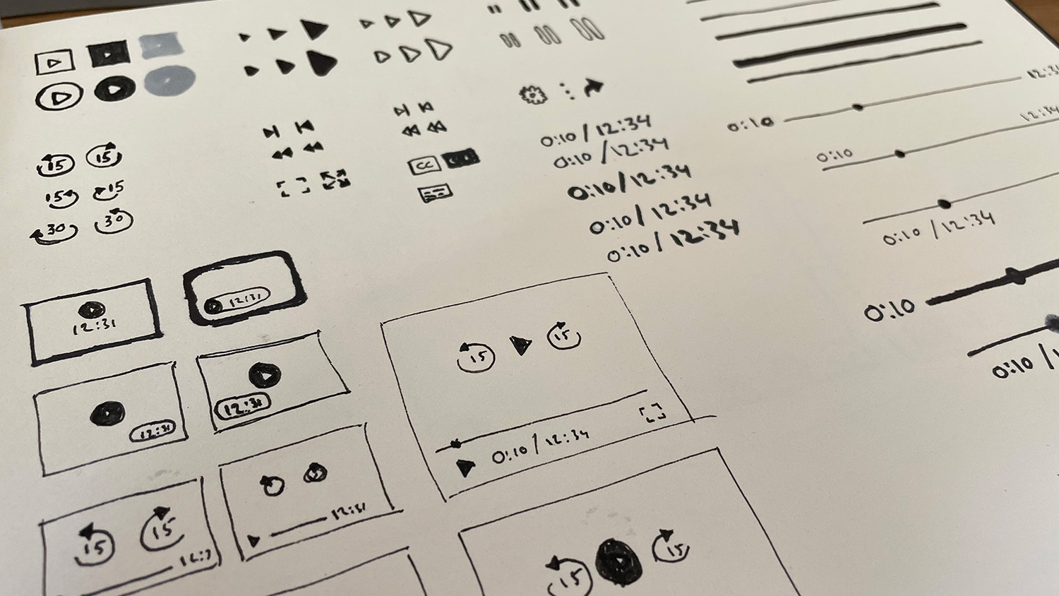 A sketchbook page with play button shapes, skip icons, time displays, progress bars and small player layouts.